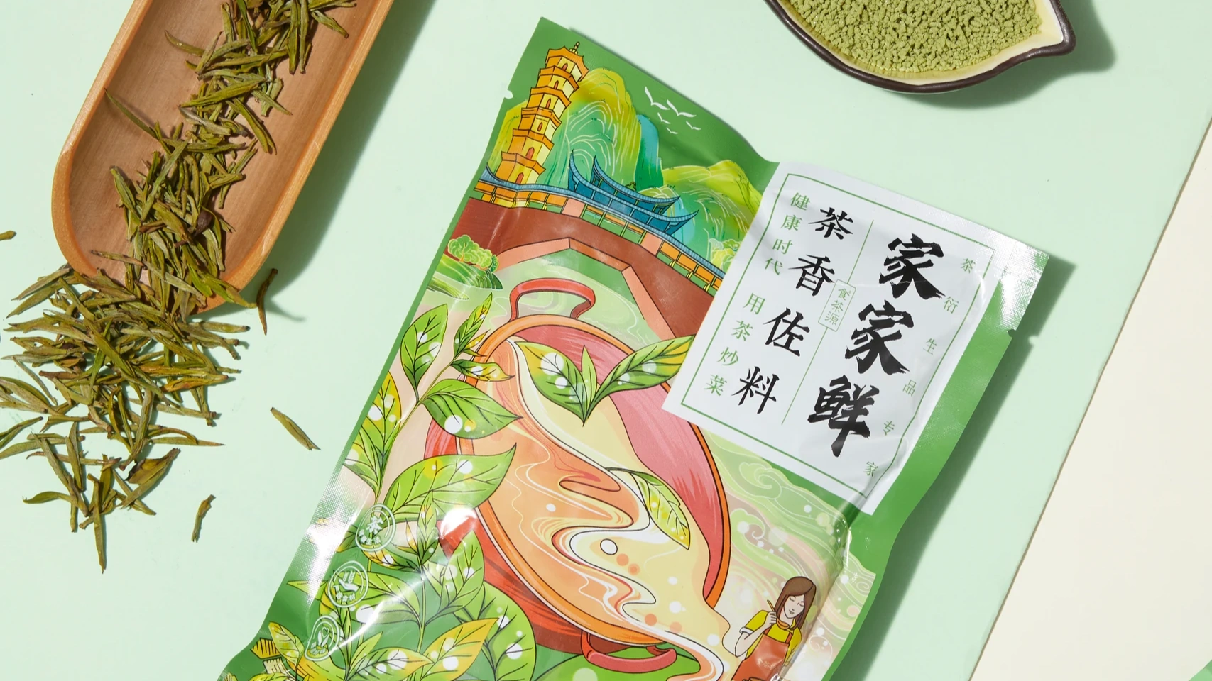 以绿色、粉色台面搭配茶叶与木勺，展示袋装茶的包装和内容物。